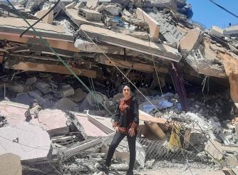 صورة سماح كساب مسؤولة البرنامج الإنساني في مؤسسة أكشن إيد-فلسطين وهي تقف بين الدمار الذي احدثته  الغارات الجوية الإسرائيلية 