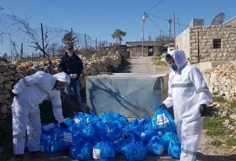 أفراد من الععاملين والمتطوعين من مؤسسة آكشن ايد-فلسطين يوزعون المواد التعقيمية والصحية على سكان بيت سكاريا وهي منطقة تقع في الجنوب الغري من بيت لحم في جنوب الضفة الغربية ضمن ججهود المؤسسة للااستجابة لمكافحة فيروس كورونا