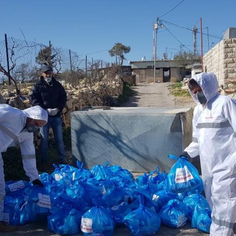 أفراد من الععاملين والمتطوعين من مؤسسة آكشن ايد-فلسطين يوزعون المواد التعقيمية والصحية على سكان بيت سكاريا وهي منطقة تقع في الجنوب الغري من بيت لحم في جنوب الضفة الغربية ضمن ججهود المؤسسة للااستجابة لمكافحة فيروس كورونا