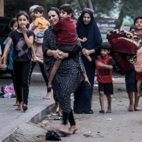 صورة لنساء يحملن أطفالهن ويهربن من القصف الإسرائيلي في أحد شوارع مدينة غزة (أ.ف.ب) 