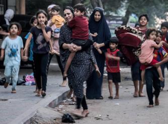 صورة لنساء يحملن أطفالهن ويهربن من القصف الإسرائيلي في أحد شوارع مدينة غزة (أ.ف.ب) 